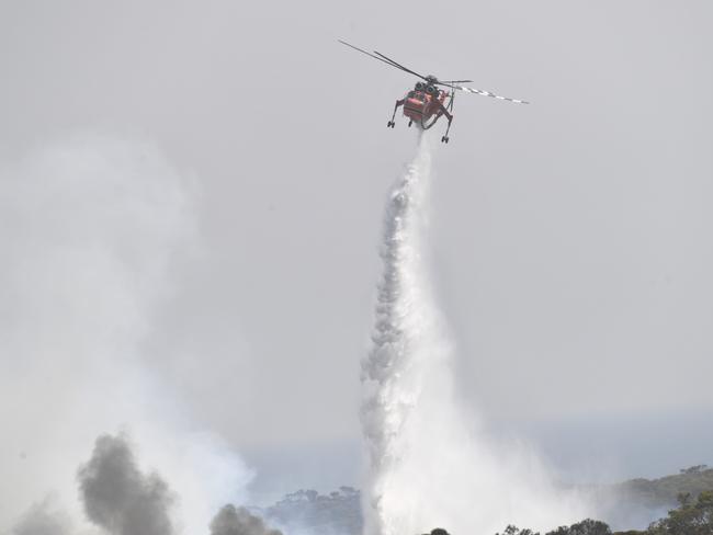 A helicopter drops water on bushfires sweeping through Stokes Bay on Kangaroo Island, southwest of Adelaide. Picture: AAP