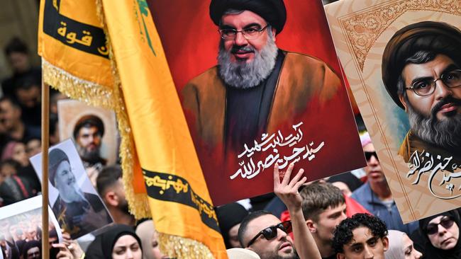 Demonstrators hold flags and pictures of Nasrallah in the Sydney CBD. Picture: AAP