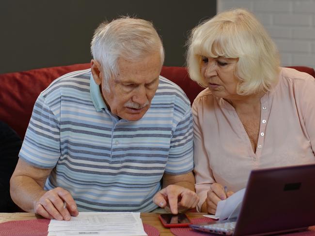 Worried senior retired couple checking calculating bills bank loan payment doing paperwork discuss unpaid debt taxes at home. Stressed old mature grandparents family upset about money problem concept; retirees generic