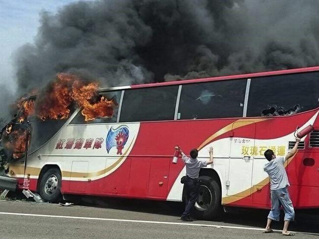 In this photo provided by Yan Cheng, a policeman and another man try to break the windows of a burning tour bus on the side of a highway in Taoyuan, Taiwan, Tuesday, July 19, 2016. The tour bus carrying visitors from China burst into flames on a busy highway near Taiwan's capital on Tuesday, burning to death over 20 people on board, officials said .(Yan Cheng/Scoop Commune via AP)