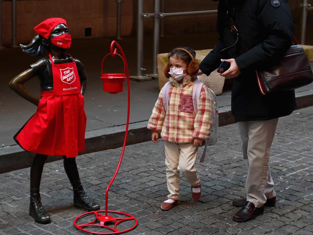 New York’s “fearless girl” masks up as she meets a real-life counterpart. Picture: AFP