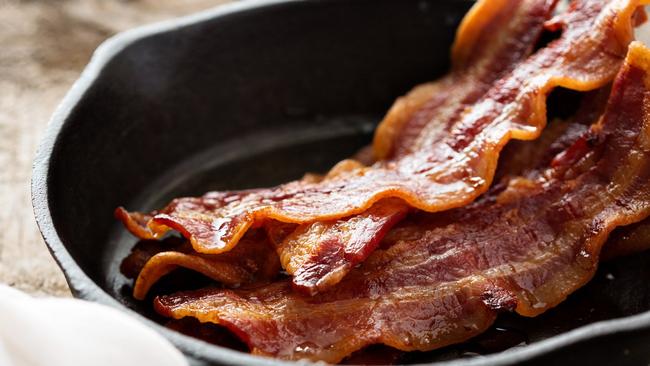 Sizzling hot bacon pieces in a cast iron skillet