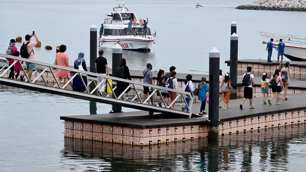 Tourists walk towards passenger ferries to travel from Sanur to Nusa Penida island. Picture: SONNY TUMBELAKA / AFP