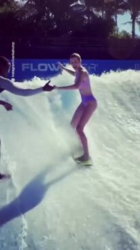 Ivanka Trump surfs a flowrider machine in a purple swimsuit