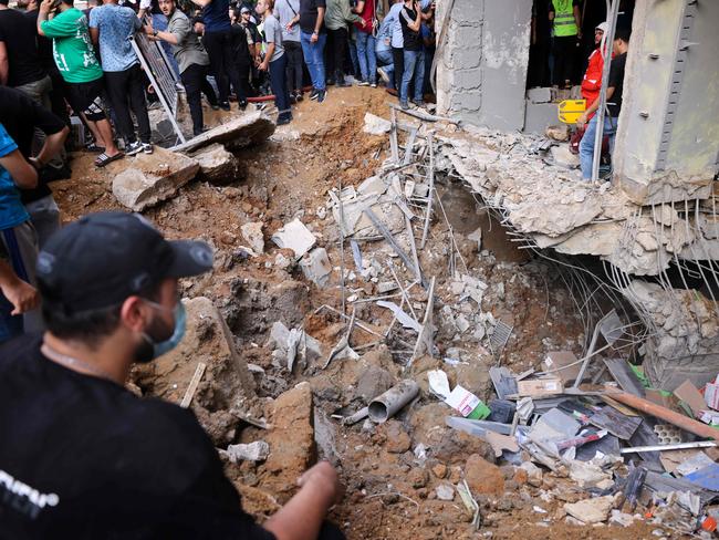 People and first responders gather in front of a building targeted by the Israeli strike. Picture: AFP.