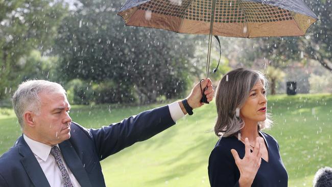 Health Minister Stephen Wade holds an umbrella over chief public health officer Nicola Spurrier as she discusses the decision to grant a travel exemption to Collingwood. Picture: NCA NewsWire / David Mariuz