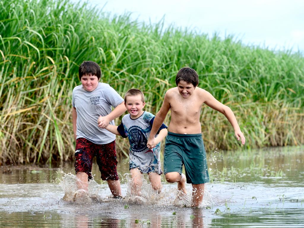 Roman, 10, Raymond-John, 6, and Kristopher Matthews, 12, play in a flooded canefield next to their Ayr home. Pictured: Scott Radford-Chisholm