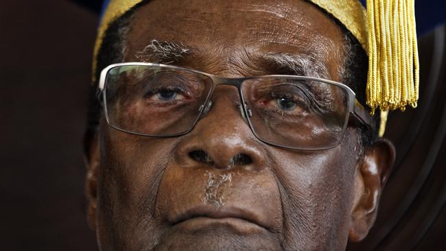 Zimbabwe's President Robert Mugabe sits for formal photographs with university officials, after presiding over a student graduation ceremony at Zimbabwe Open University on the outskirts of Harare, Zimbabwe Friday, Nov. 17, 2017. Mugabe made his first public appearance since the military put him under house arrest earlier this week. (AP Photo/Ben Curtis)