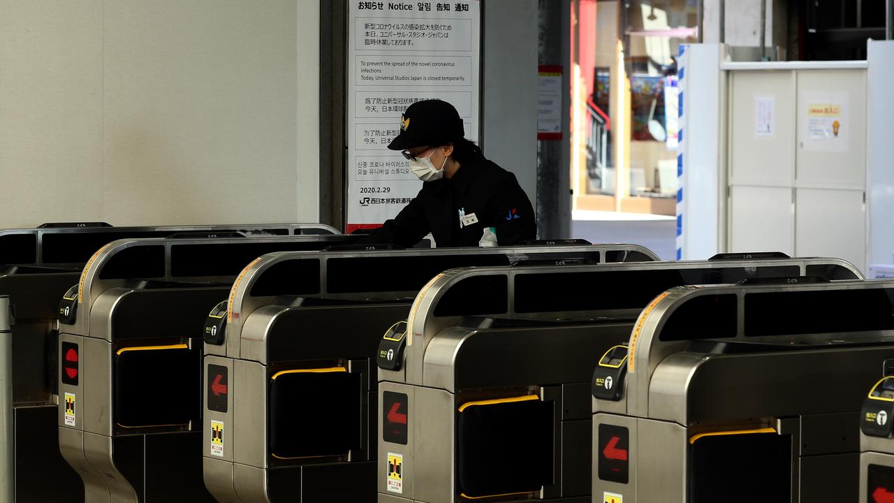 A Japan railway staff wears a face mask while cleaning the entrance of Universal Studio station on March 05, 2020 in Osaka, Japan. Picture: Buddhika Weerasinghe