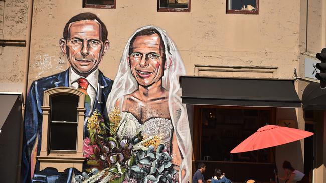 A mural by Australian street artist Scottie Marsh depicts former Australian prime minister Tony Abbott marrying himself on the wall of a cafe in Sydney on September 22, 2017.  Abbott, an outspoken critic of same-sex marriage, said he was headbutted by a man wearing a "yes" badge, raising fears campaigning ahead of a postal vote was turning violent. / AFP PHOTO / PETER PARKS