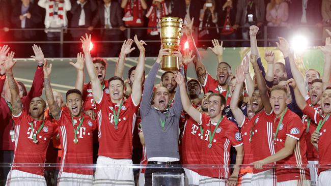 Bayern head coach Pep Guardiola holds up the trophy.