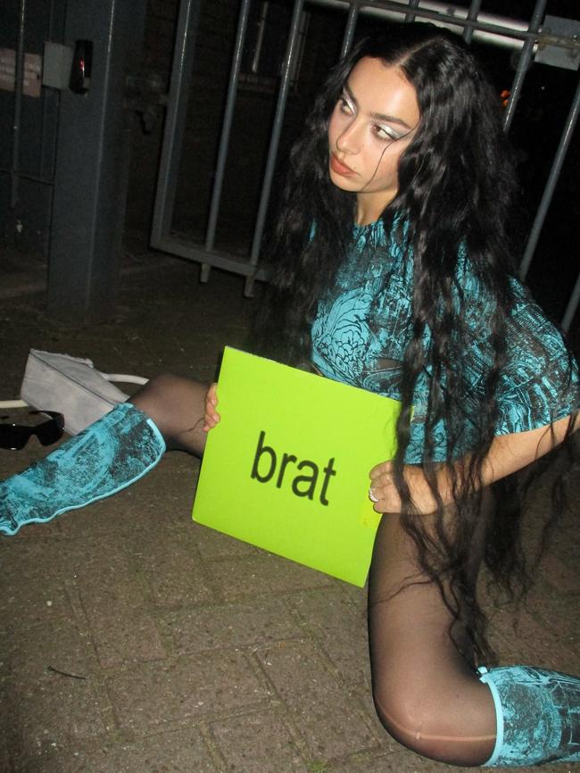 Charli with the vinyl pressing of ‘Brat’, printed in recognisable fluorescent green.