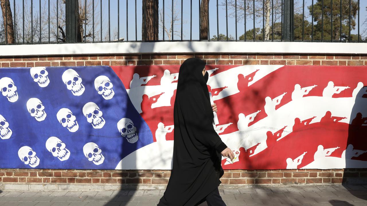 A mourner walk back from a funeral ceremony for Iranian Gen. Qassem Soleimani and his comrades, who were killed in Iraq in a US drone attack on Friday, passing graffiti on the wall of the former US Embassy in Tehran, Iran. Picture: AP/Vahid Salemi