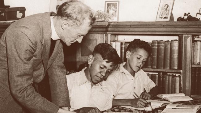 Father Smith helps future AFL footballer Malcolm Cooper and future indigenous rights activist Charles Perkins with their homework. Picture: Courtesy of St Francis House Project