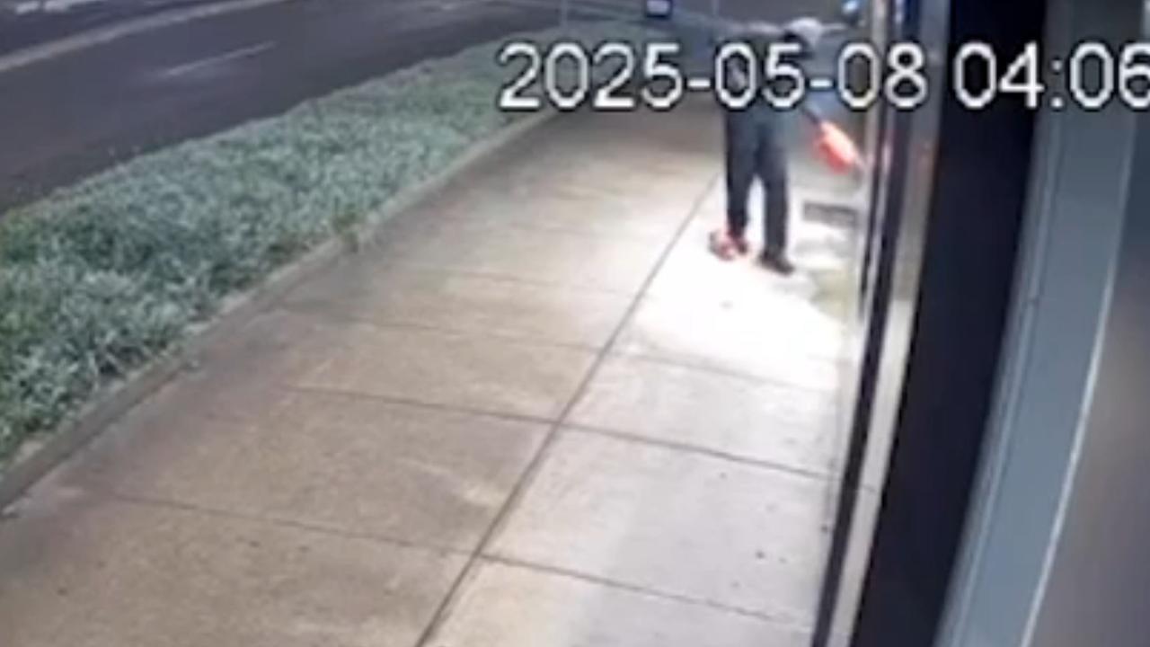 The incredible footage shows a hooded man dressed in black scampering down the foot path of Merrylands Rd towards a barber shop with two items in his hand just after 4am. Picture: Supplied