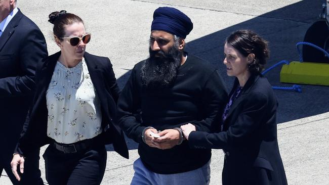 Queensland Police officers and detectives escort Rajwinder Singh from a chartered jet to a waiting police car at Cairns Airport after being extradited from New Delhi to Cairns via Melbourne. Picture: Brendan Radke