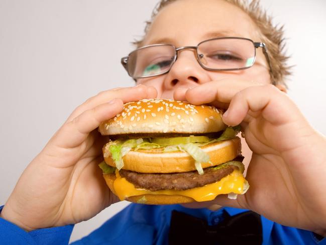 Young fat school boy eating hamburger