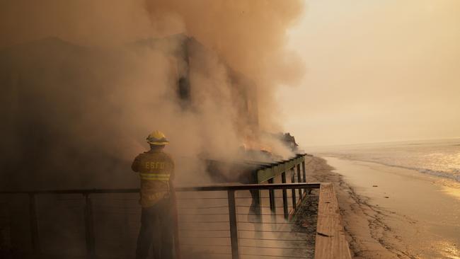 A firefighter protects a beachfront property while fighting the Palisades Fire in Malibu. Picture: AP