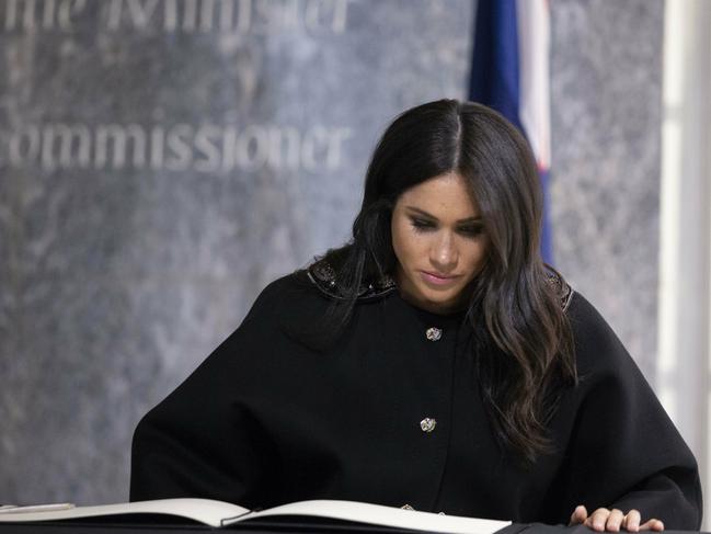 The Duchess of Sussex signs the book of condolence, during a visit to the New Zealand High Commission in London. Picture: AP