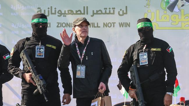 Palestinian militant group Hamas fighters escort American-Israeli hostage Keith Siegel on a stage before handing him over to a Red Cross team in Gaza City.