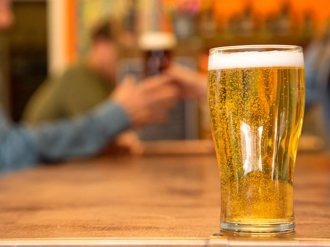 bartender handing customer a stout beer in out of focus background with cold pale beer in foreground