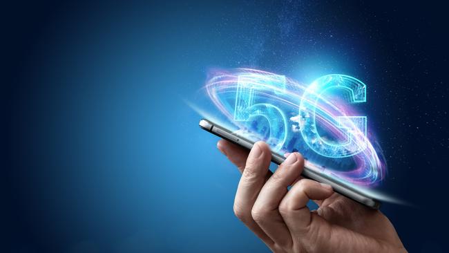 Creative background, male hand holding a phone with a 5G hologram on the background of the city. The concept of 5G network, high-speed mobile Internet, new generation networks. Copy space, Mixed media. Generic istock