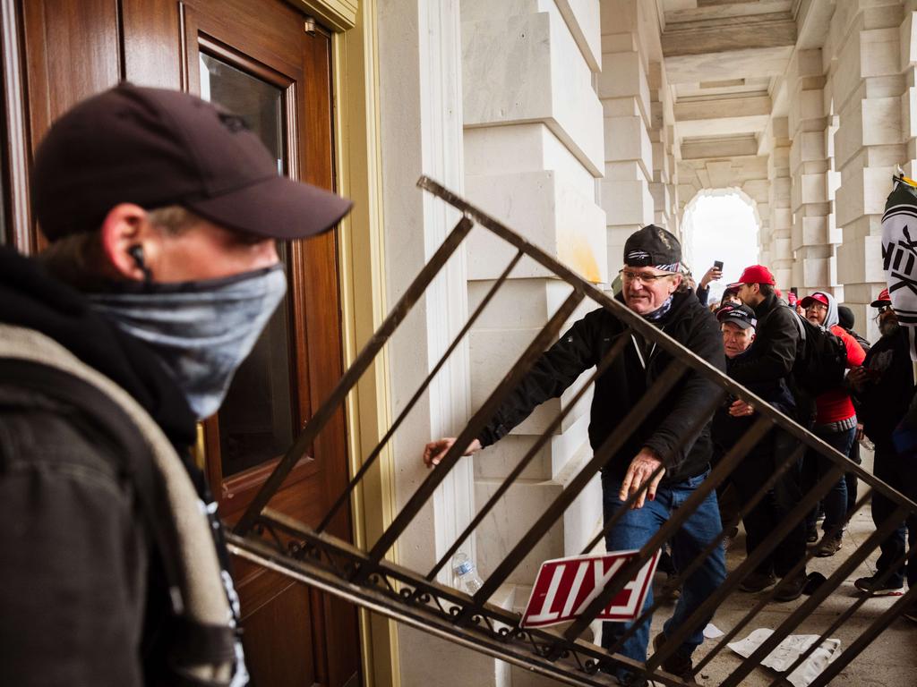 A member of a pro-Trump mob bashes an entrance of the Capitol Building in an attempt to gain access on January 6. Picture: Jon Cherry/Getty Images/AFP