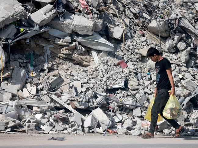 A youth carrying some belongings walks amid the rubble of destroyed buildings as people reach the central Gaza Strip via the Salah al-Din road on their way to the southern part of the Palestinian enclave. Picture: AFP