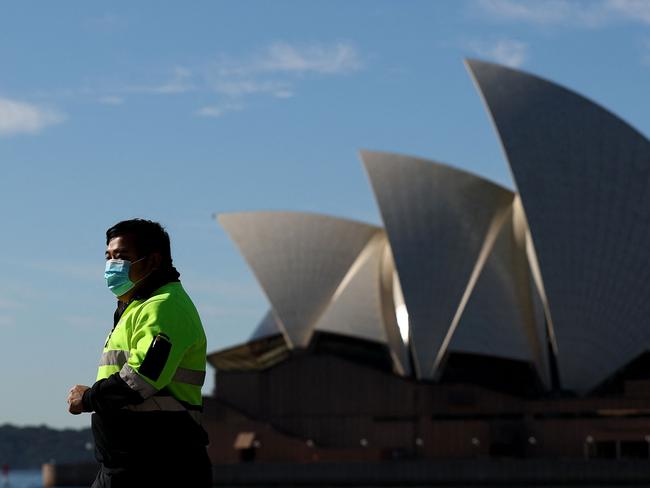 A man wearing a face mask walks past the Opera House in Sydney on July 13, 2021, during a lockdown as authorities stepped up efforts to curb a fast-growing coronavirus outbreak. (Photo by Brendon THORNE / AFP)