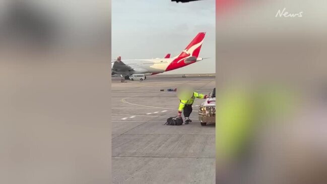 Qantas baggage handler stops to pick luggage that fell off the back of his vehicle