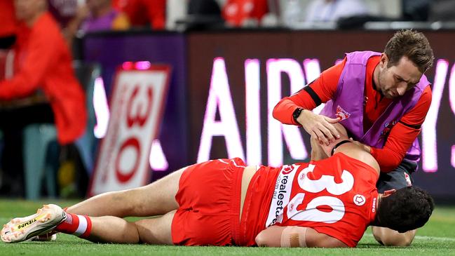 Paddy McCartin of the Swans receives attention from a trainer after knocking his head.