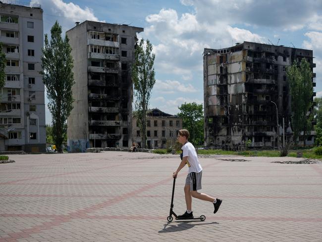 A boy scooters past bomb destroyed buildings that are waiting to be demolished. Picture: Getty