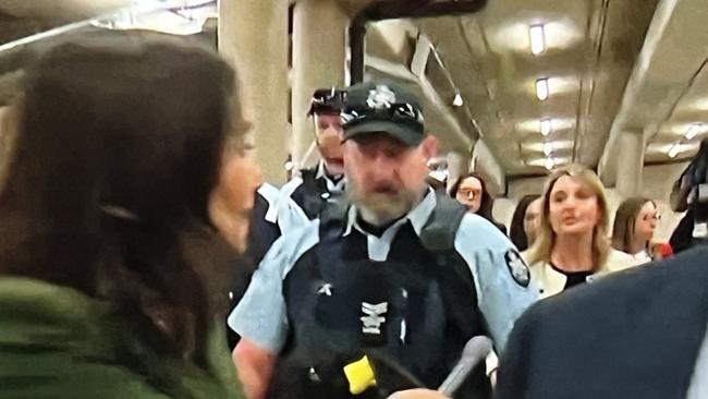 Optus CEO Kelly Bayer Rosmarin (in cream) being escorted by AFP at Parliament House in Canberra. Picture: Sky News