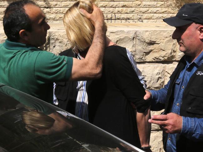 Lebanese policemen force Tara Brown into a car while escorting her to a Lebanese courthouse. Picture:  AFP.