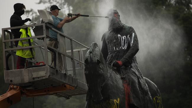 Workers clean graffiti from a statue of Belgium's King Leopold II in Brussels. Picture: AP Photo/Francisco Seco