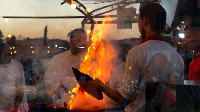 Moroccan men cook dinner on an open fire at Djemaa el Fna square in Marrakech.