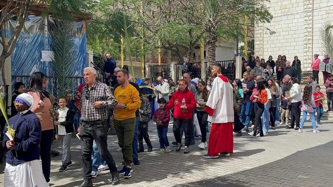 Gaza Christians walk slowly in a procession past the stone facade of Gaza's only Catholic church on Palm Sunday, gathering to pray for peace as war raged around them. Picture: AFP