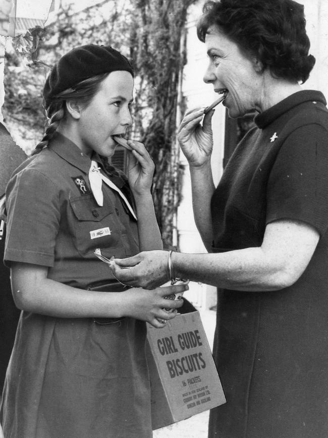 Brownie Felicity McEwin, 10, and SA Governor's wife Lady Harrison, president of the Girl Guides Association, eat Girl Guides biscuits at Government House, 1969.