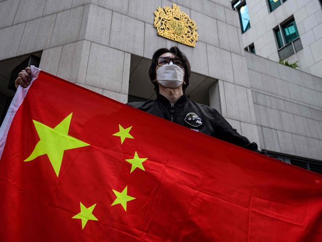 An man holds the national flag of China after a pro-Beijing activist group gathered outside the British Consulate-General to protest against the use of the British National (Overseas) passport in Hong Kong on February 1, 2021, as a new visa scheme offering millions of Hong Kongers a pathway to British citizenship went live the day before. (Photo by Anthony WALLACE / AFP)