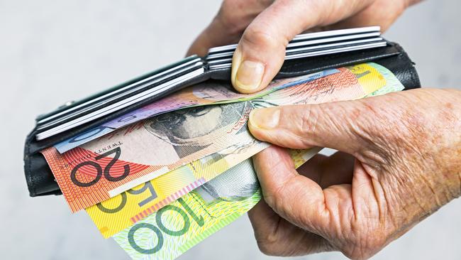 Close-up, senior female hands taking Australian banknotes (cash, currency) from purse containing many credit cards.  Horizontal, studio, copy space. Money generic