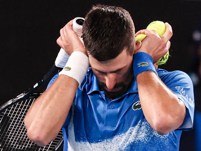 TOPSHOT - Serbia's Novak Djokovic covers his ears as he reacts to spectators making noise while he was about to serve against Czech Republic's Jiri Lehecka during their men's singles match on day eight of the Australian Open tennis tournament in Melbourne on January 19, 2025. (Photo by DAVID GRAY / AFP) / -- IMAGE RESTRICTED TO EDITORIAL USE - STRICTLY NO COMMERCIAL USE --