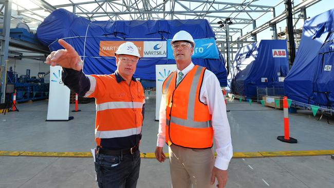 AGL executive Colin Mills and SA Energy Minister Dan van Holst Pellekaan in front of the first of twelve engines delivered to the new Barker Inlet Power Station. Picture: AAP/Mark Brake