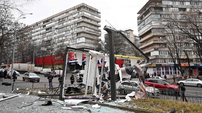 People are seen outside the cordoned off area around the remains of a shell in a street in Kyiv. Picture: Sergei Supinsky / AFP