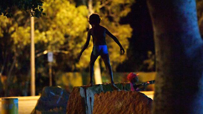 A young child plays as his family sit beside the road near the BP service station in Tennant Creek after 10pm.