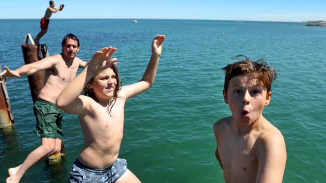 Shannon Breuer, 44, (third from right) and his boys enjoy jetty-jumping at Glenelg. Picture: Dean Martin