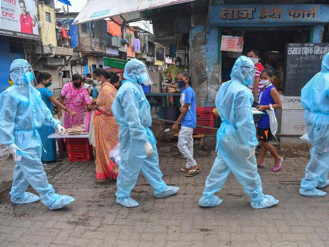 Medical staff walk through a market for door-to-door medical screening at a Mumbai slum. Picture: AFP