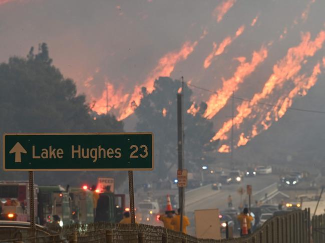 Flames from the Hughes Fire burn a hillside in Castaic, a northwestern part of Los Angeles County, California, on January 22, 2025. A new wildfire erupted north of Los Angeles on January 22, exploding in size and sparking thousands of evacuation orders in a region already staggering from the effects of huge blazes. Ferocious flames were devouring hillsides near Castaic Lake, spreading rapidly to cover 5,000 acres (2,000 hectares) in just over two hours. The fire was being fanned by strong, dry Santa Ana winds that were racing through the area, pushing a vast pall of smoke and embers ahead of the flames. Evacuations were ordered for 19,000 people all around the lake, which sits around 35 miles north of Los Angeles, and close to the city of Santa Clarita. (Photo by Robyn Beck / AFP)