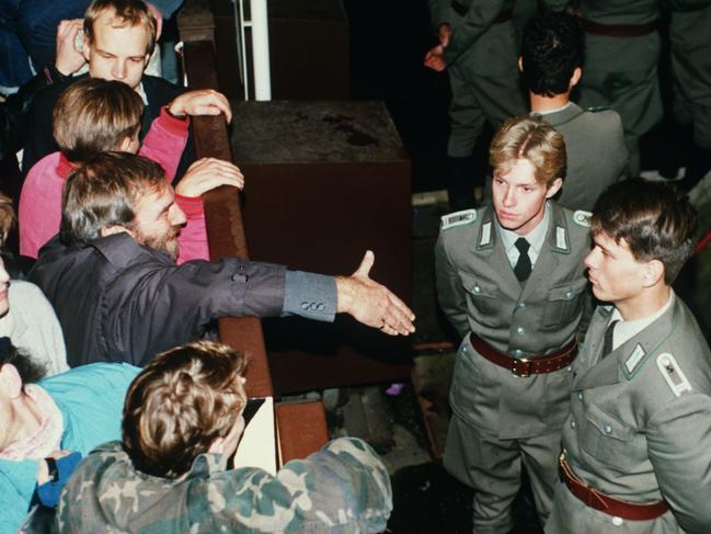 East German border policemen, right, refusing to shake hands with a Berliner who stretches out his hand over the border fence. Picture: AP