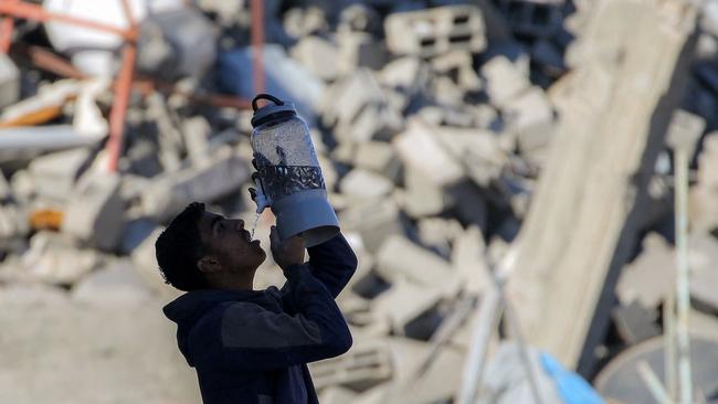 A boy drinks water from the tap of a dispenser in the rubble of a collapsed building in Rafah in the southern Gaza Strip. Picture: AFP