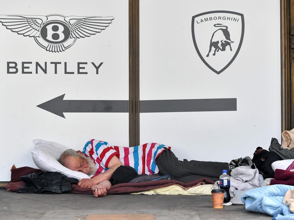 A homeless man sleeps in front of a luxury dealership in San Francisco. Picture: Josh Edelson/AFP